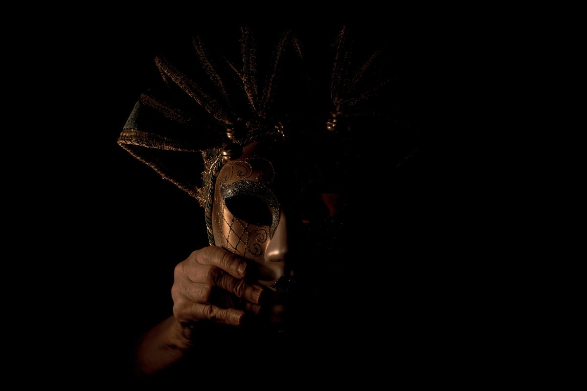 Venetian carnival mask in the dark in the hands of an old woman, masquerade and masked actor